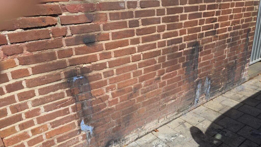 Verschmutzte Denkmalmauer mit dunklen Ablagerungen und beschädigten Fugen – Vorherbild einer Reinigung durch den Fugenbetrieb Sundarp in Eschweiler.
