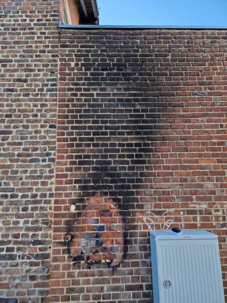 Ziegelmauer mit Ruß- und Brandschäden – Vorherbild einer Mauerwerksanierung durch den Fugenbetrieb Sundarp in Eschweiler.
